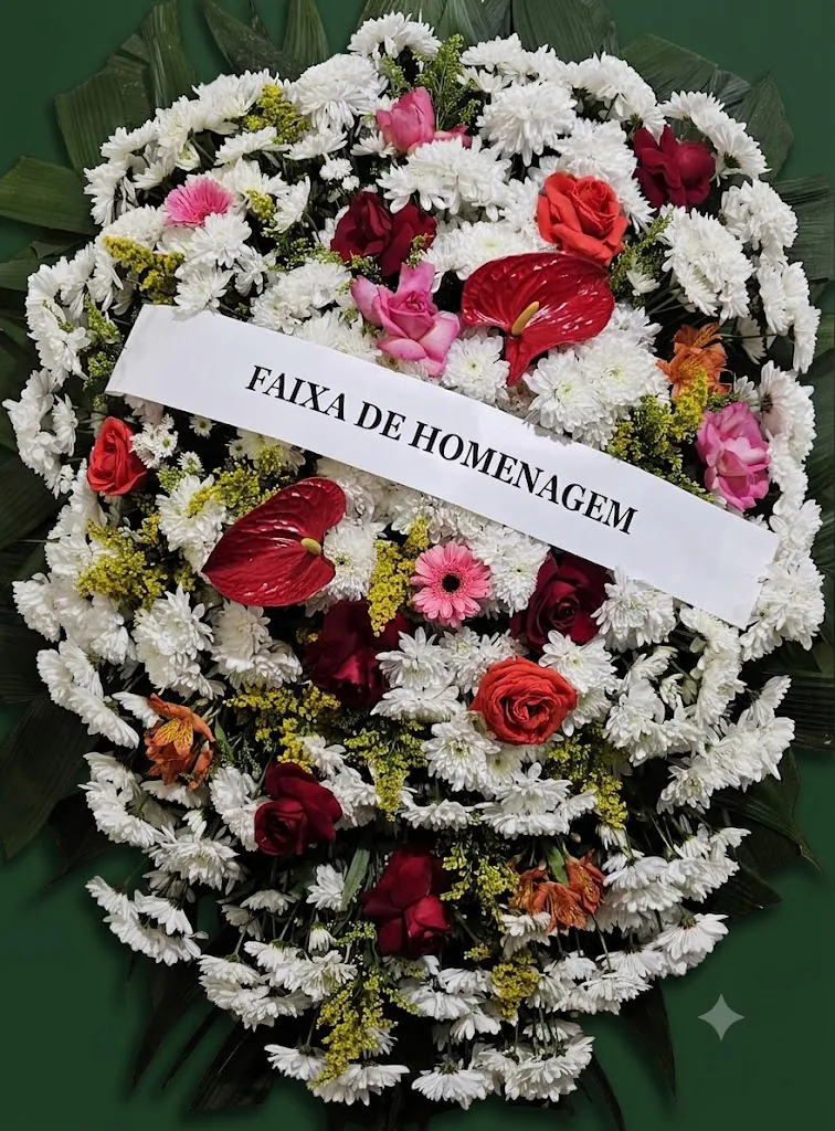 Coroa de flores brancas com rosas vermelhas e cor-de-rosa, antúrios vermelhos e faixa de homenagem