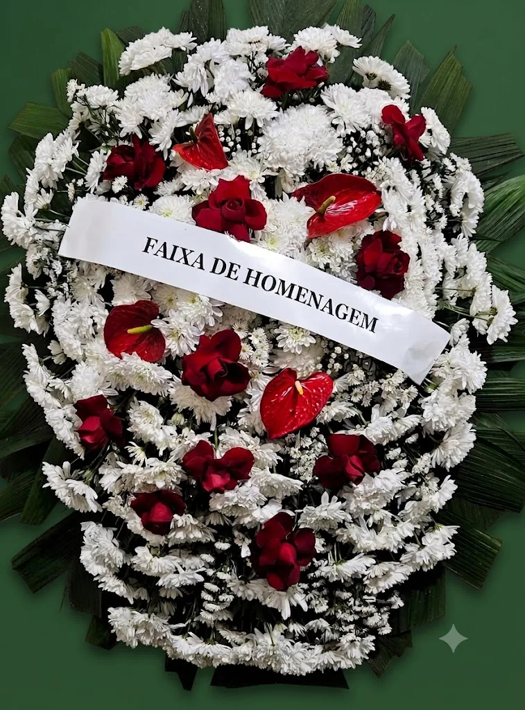 Coroa de flores brancas com rosas e antúrios vermelhos e faixa de homenagem