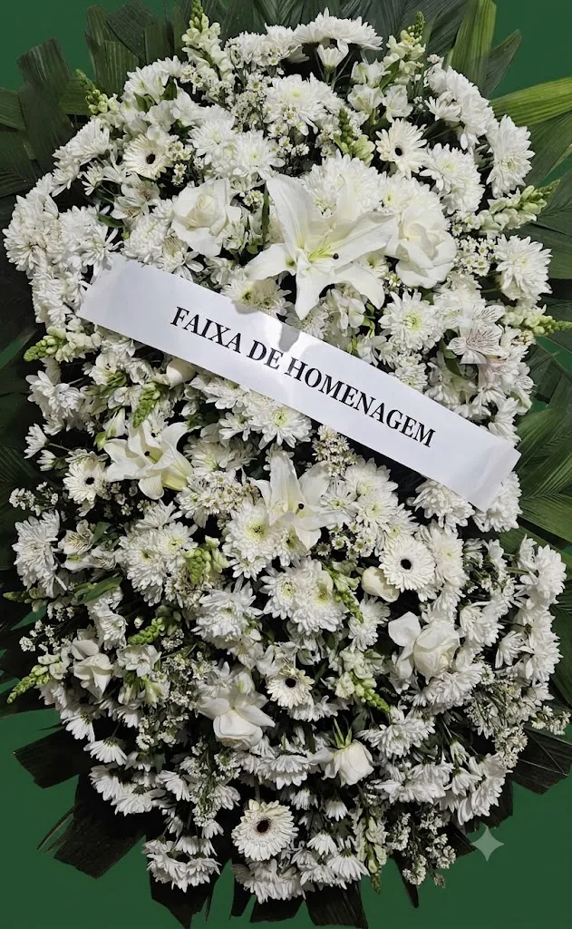 Coroa de flores brancas com lírios e faixa de homenagem